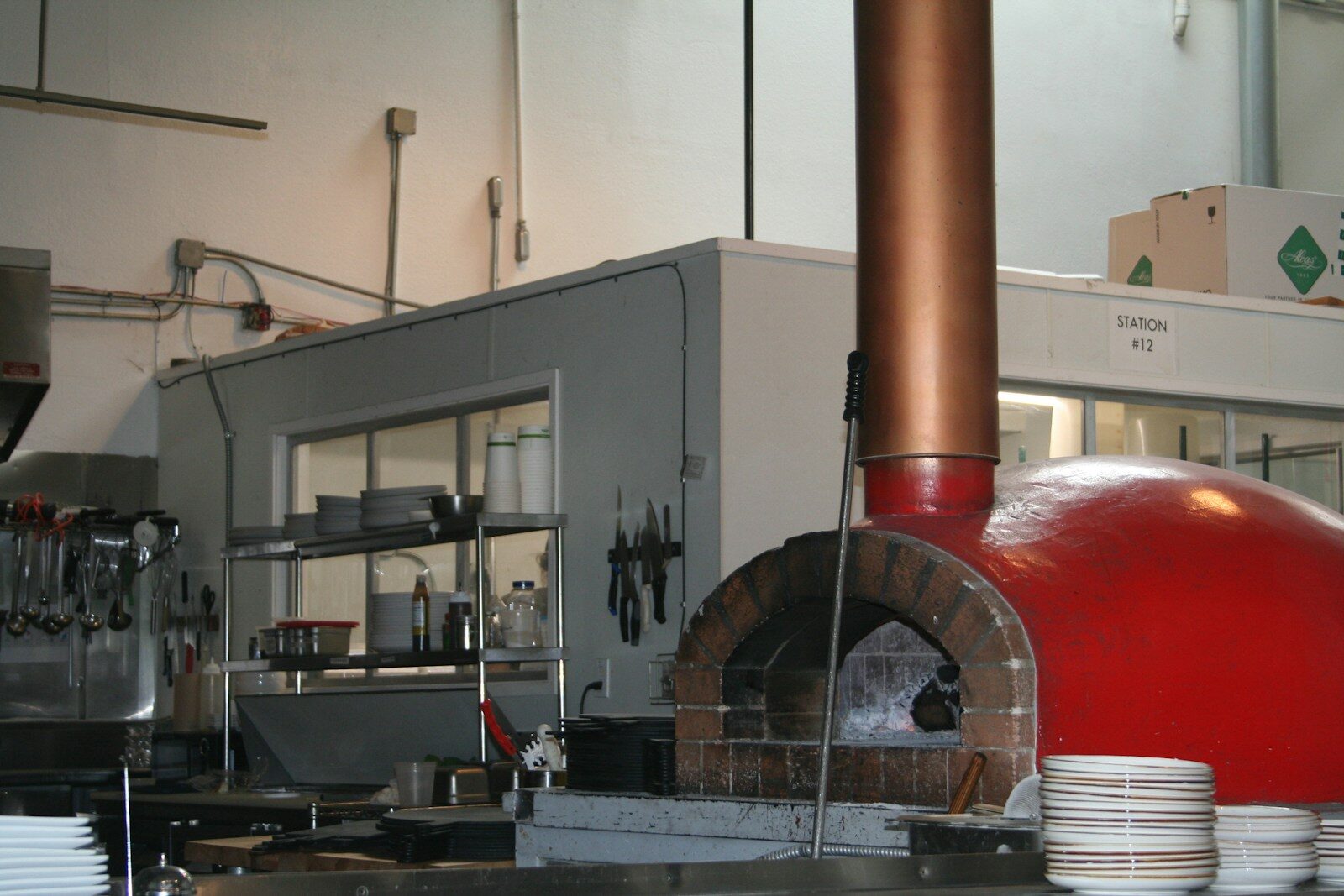A commercial kitchen features a large red brick pizza oven.